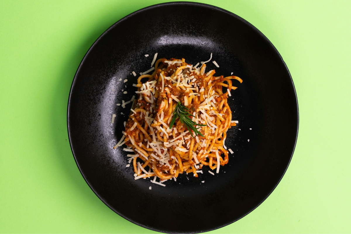 Plat de spaghetti avec parmesan sur une assiette noire, illustrant les défis d'une digestion difficile.