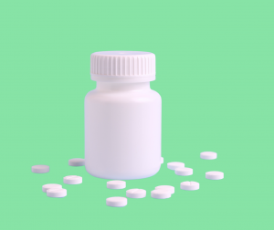 Une bouteille blanche de médicaments entourée de comprimés sur un fond vert clair, utilisée pour illustrer les causes possibles de l'insomnie