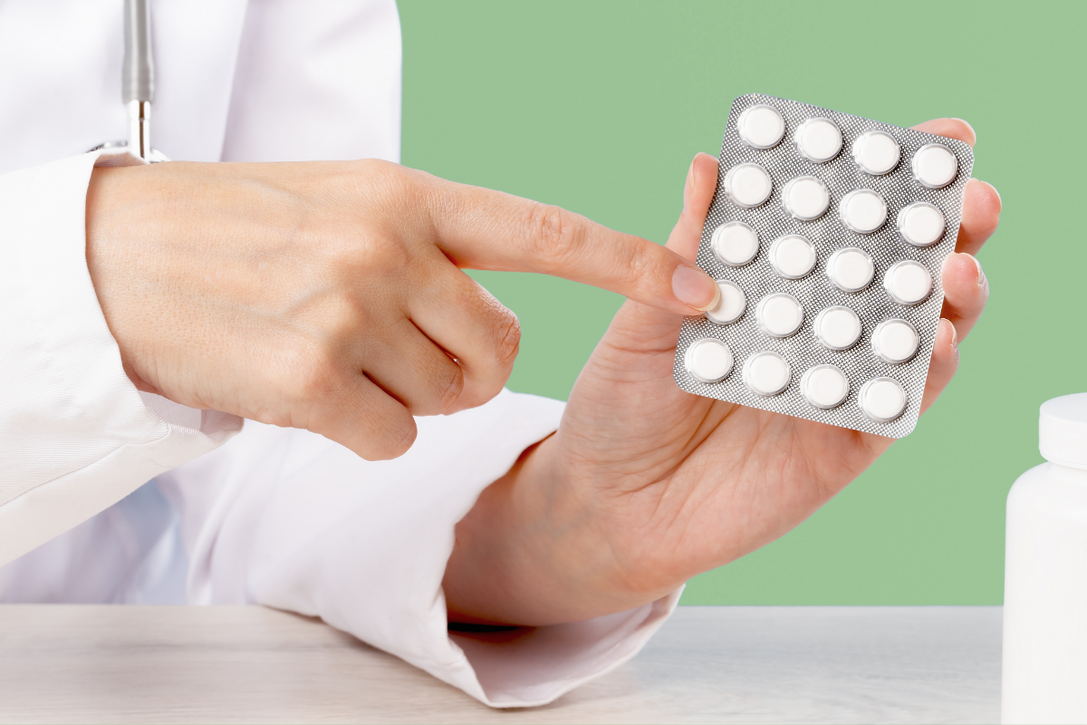 Un professionnel de santé tenant une plaquette de médicaments blancs, illustrant les traitements pouvant provoquer l'insomnie.