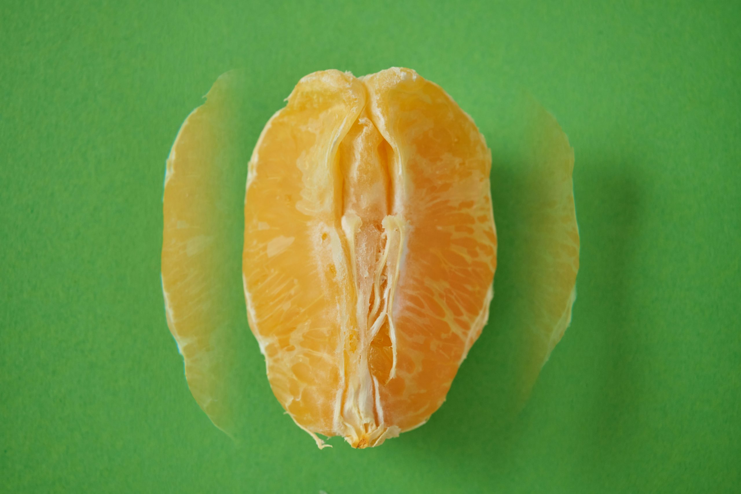Demi-mandarine pelée sur un fond vert, illustrant un aliment naturel bénéfique pour la digestion.