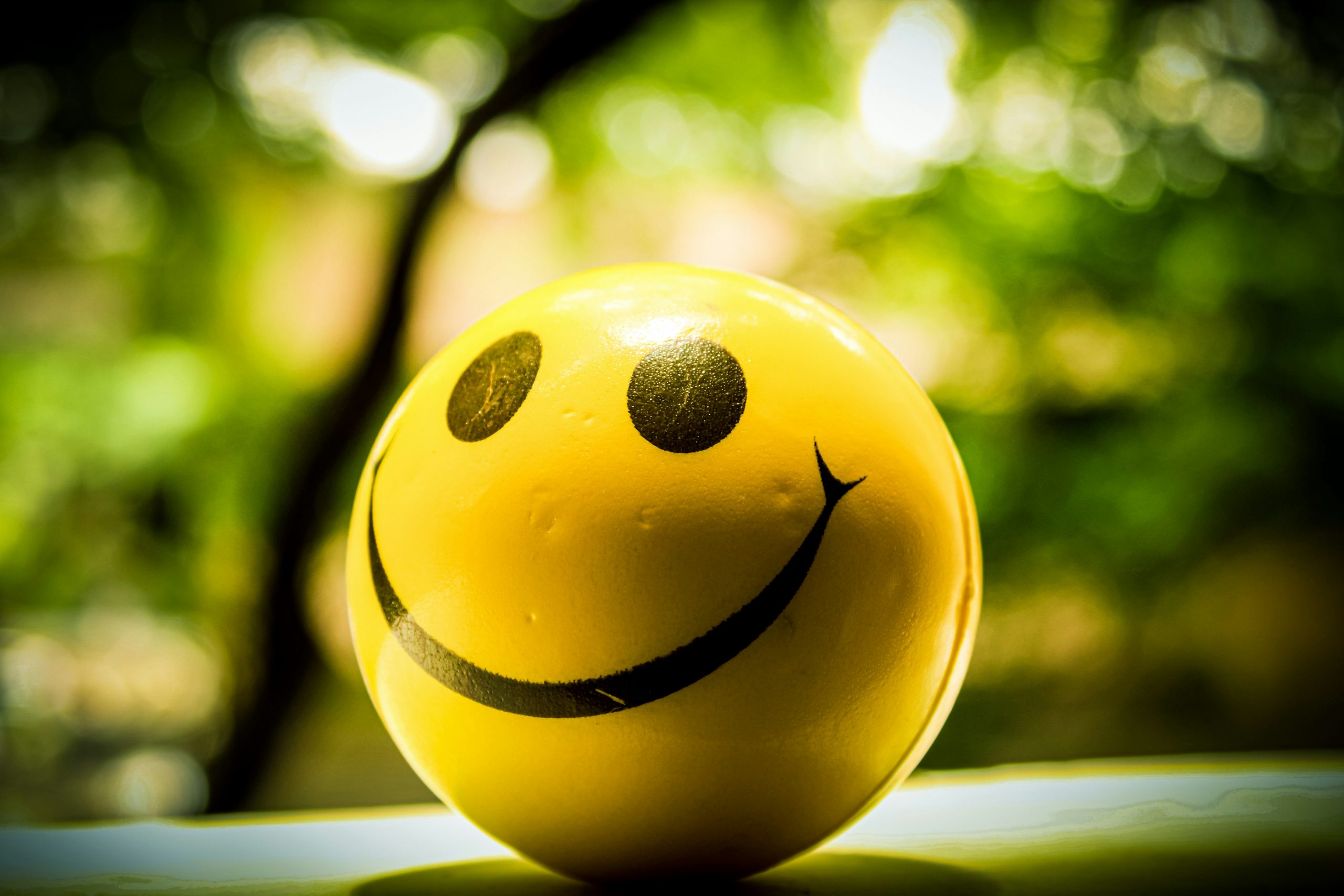 Smiley jaune souriant sur fond naturel, illustrant les bienfaits du rire pour réduire le stress et améliorer le bien-être.
