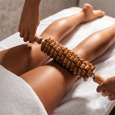 Séance de Madérothérapie réalisée sur les jambes d’une cliente, technique anti-cellulite avec rouleau en bois.